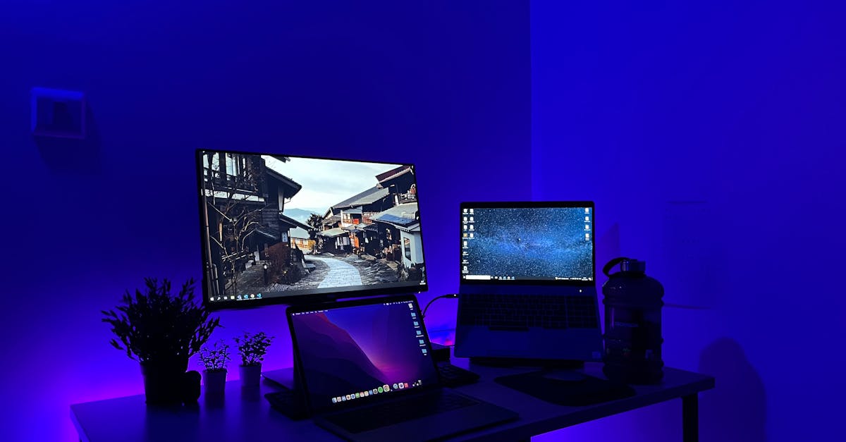 Sleek gaming desk setup with multiple screens and blue neon lighting, perfect for tech enthusiasts.